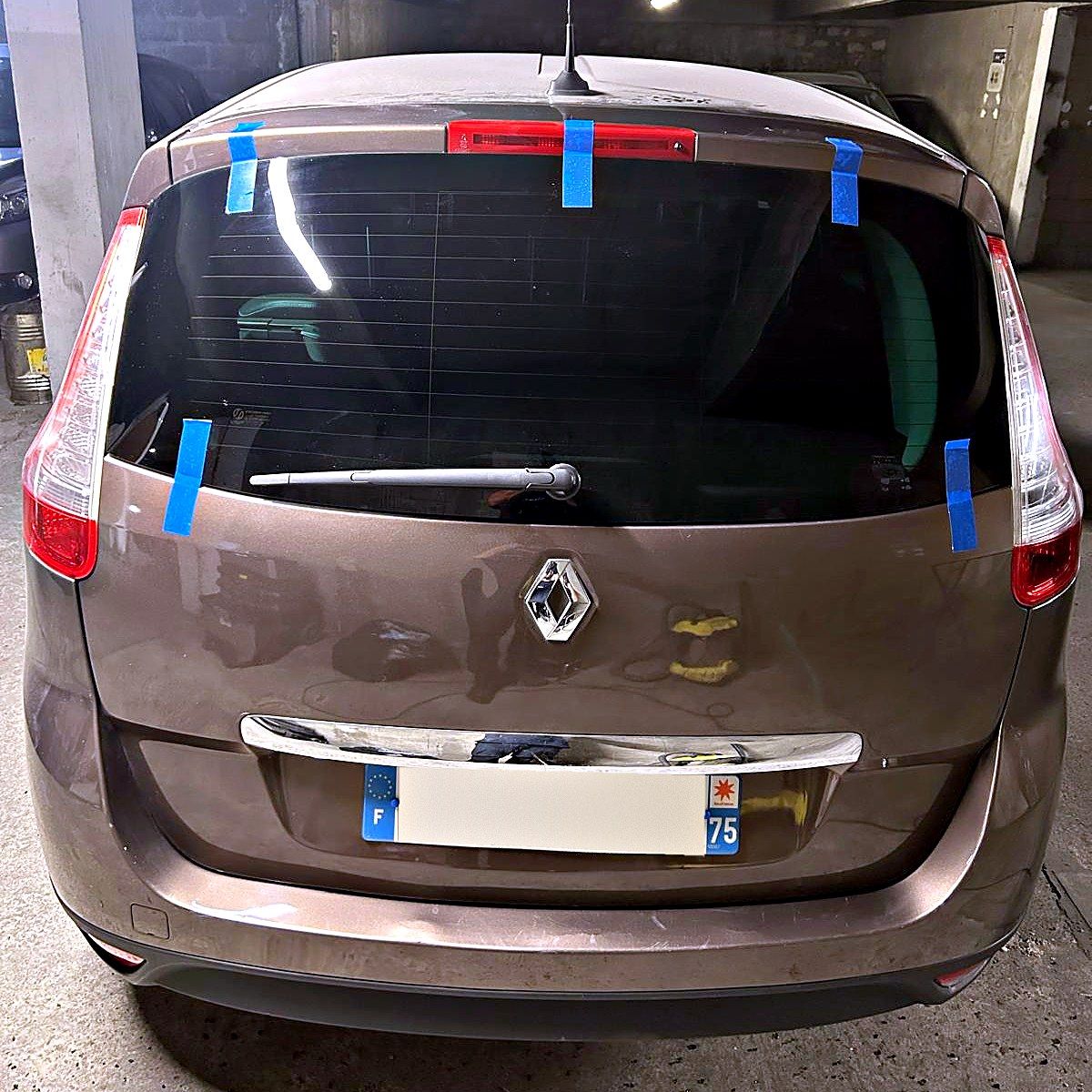Lunette arrière tout juste posée, maintenue par du ruban adhésif, sur un Renault Scénic