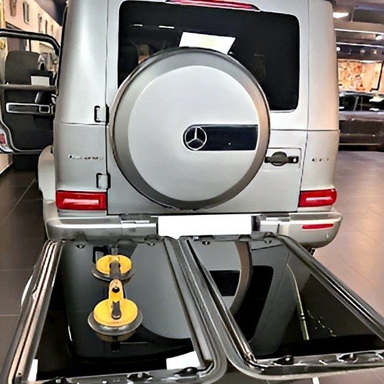 Les deux vitres d'un toit ouvrant posées sur leur support, derrière un Mercedes Classe G